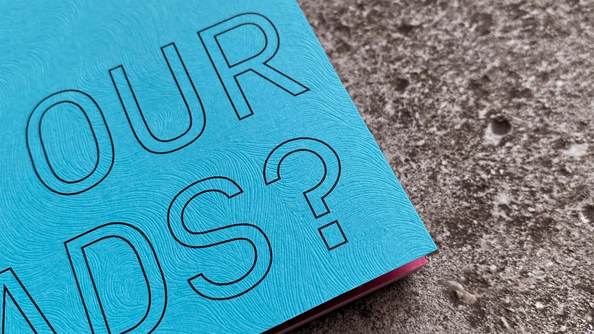 A close-up of the front cover of Dysfluent Issue 1’s cyan-coloured cover. The wave-pattern paper embossing is seen clearly.