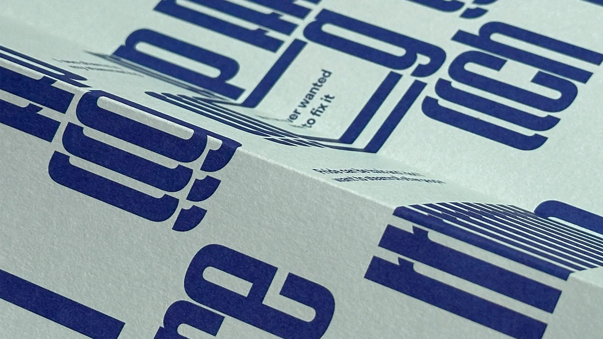 A close up of light seagreen paper with dark blue typography printed on it.