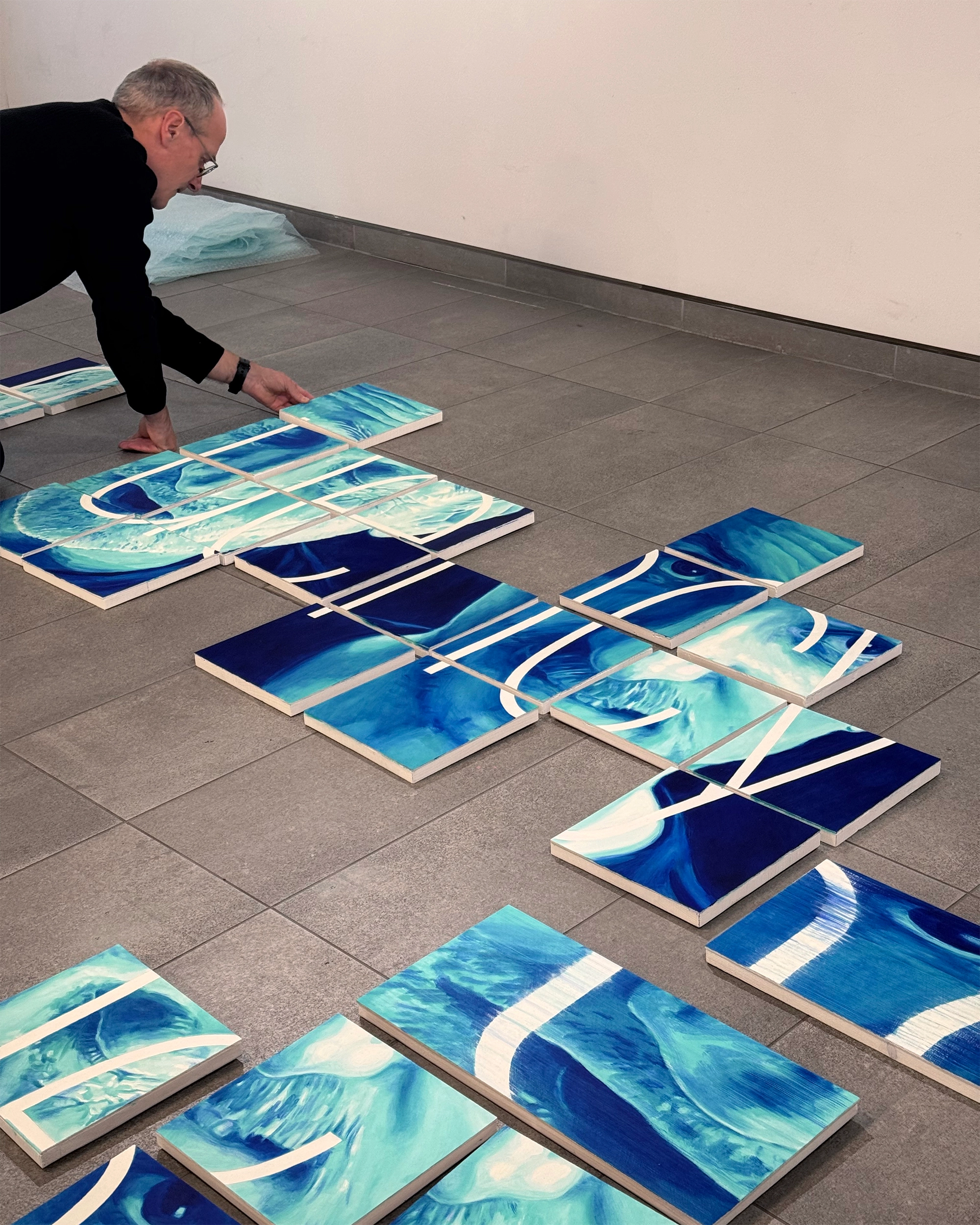 A man is on the floor arranging an artwork.