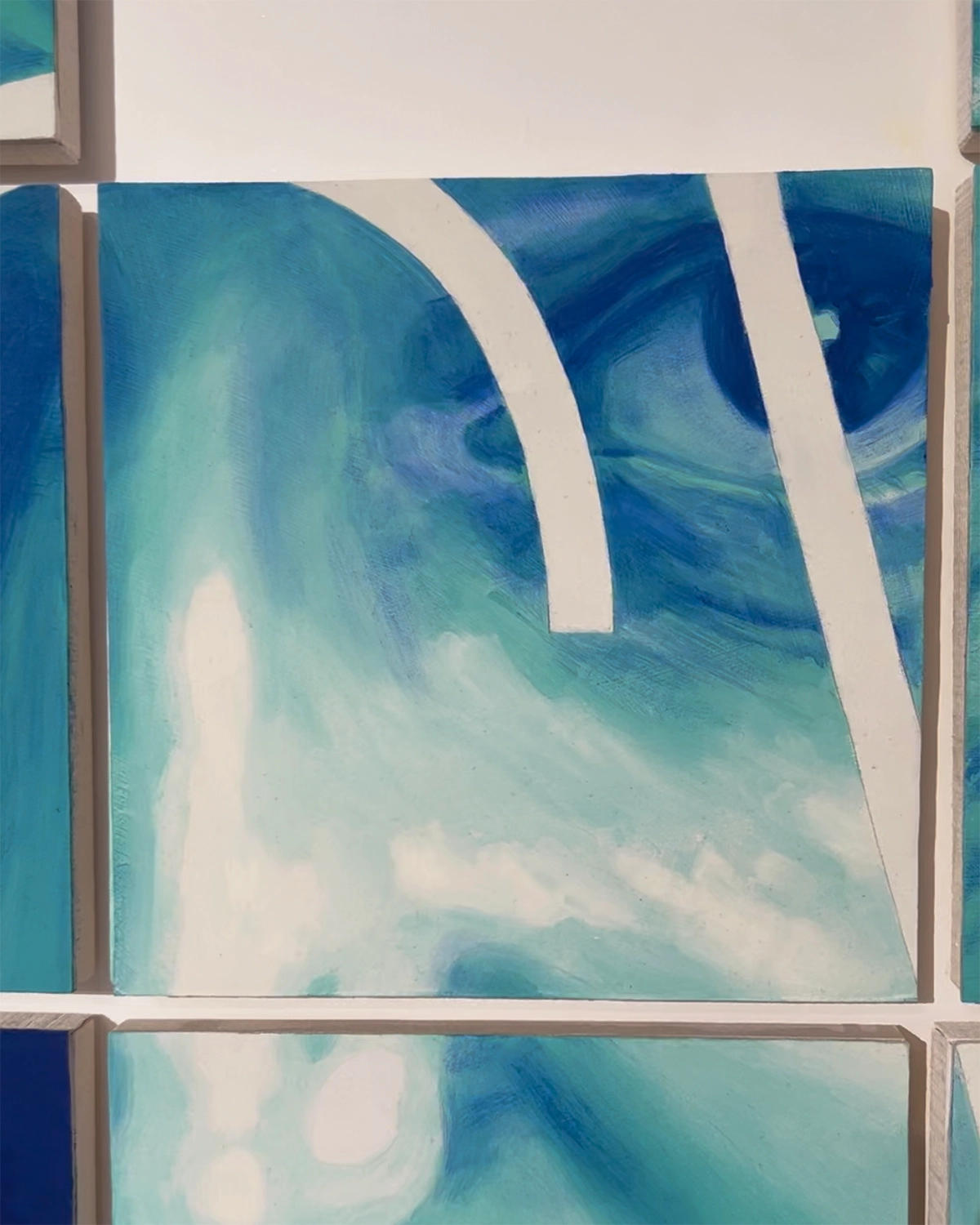 A close-up of a blue and green artwork on a white wall.