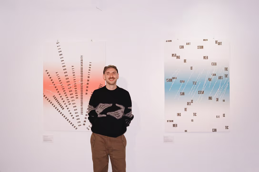 A man stands in front of artwork hung on a gallery wall.