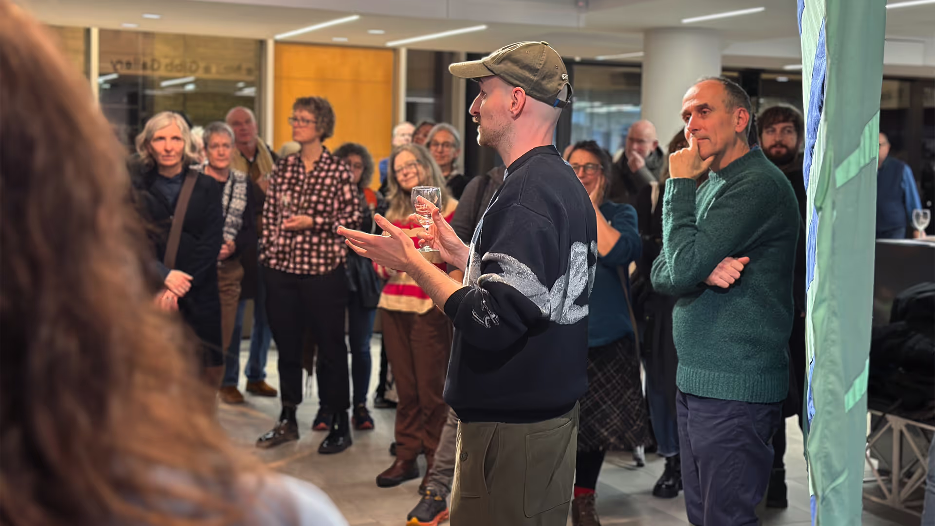 A man speaks to a crowd in a gallery.