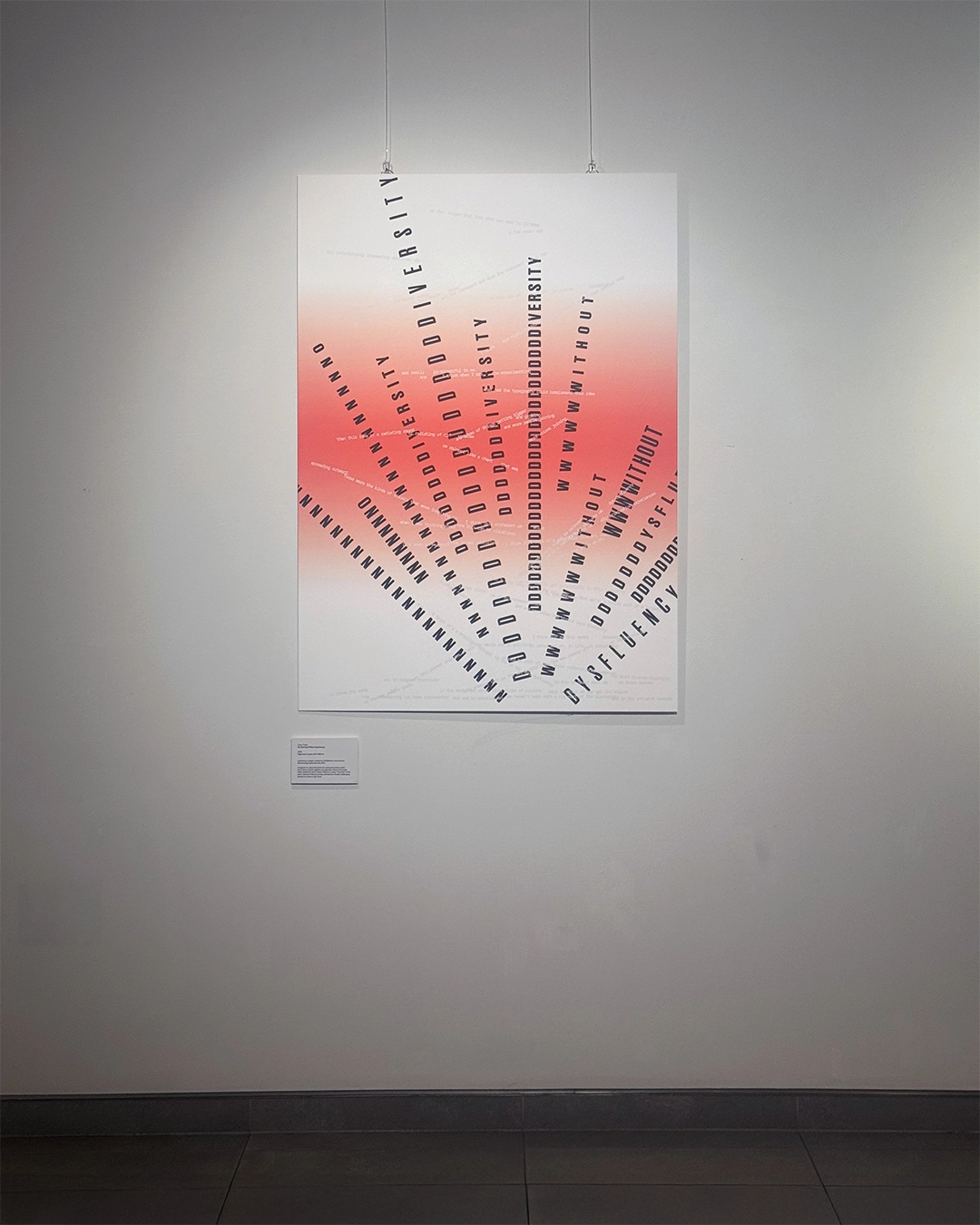 A large poster on a wall. It features a red and white gradient and a flurry of black typography, reading ‘No Diversity Without Dysfluency.’